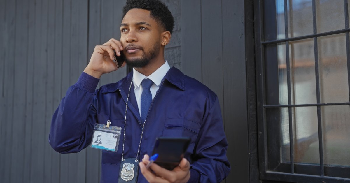 A law enforcement expert stands outside while talking on a phone. They are holding a notepad in their left hand.