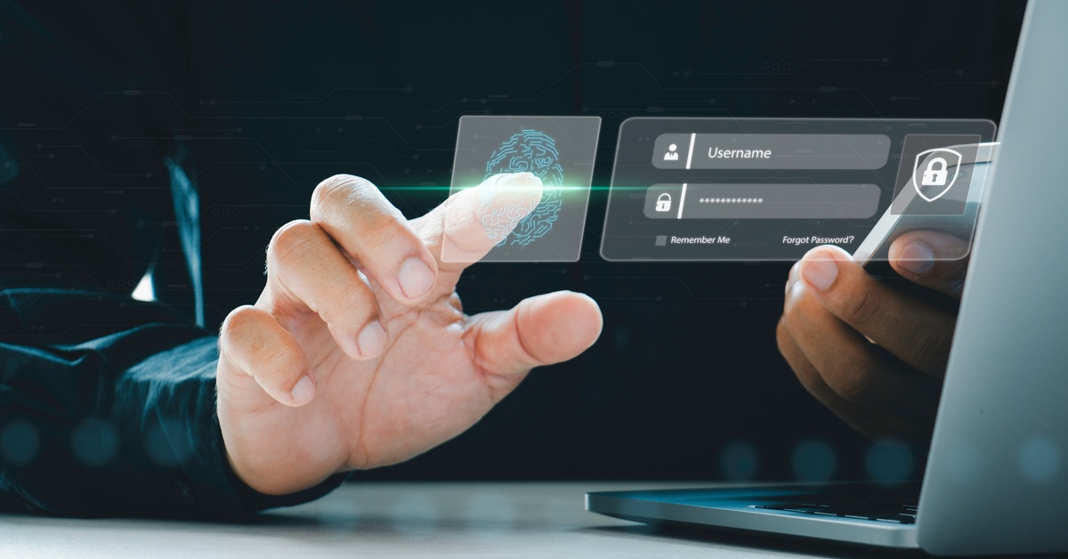 A close-up of the back of a laptop. A finger hovers over a fingerprint graphic with a username and password box next to it.
