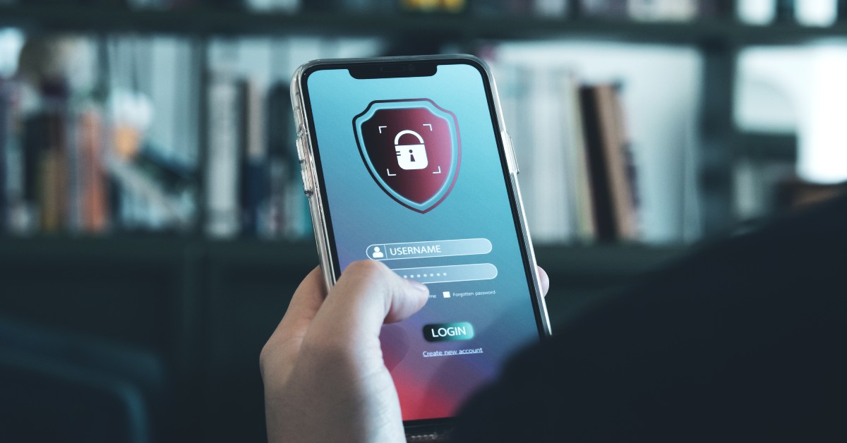 A close-up of someone holding up a smartphone. There is login informational on the screen with a lock graphic.