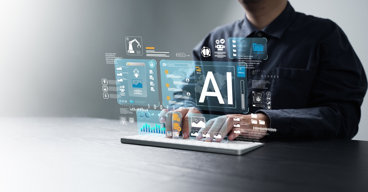 A person sitting at a desk with a keyboard in front of them. Different graphics hover over the keyboard, with the text "AI" shown.