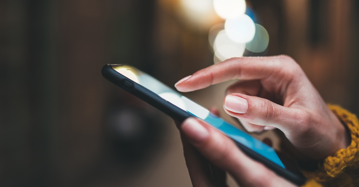 A close-up of someone holding a smartphone. They use their pointer finger to tap something on the screen.